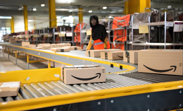 Immagine di un pacco Amazon sopra un rullo all'interno di un magazzino