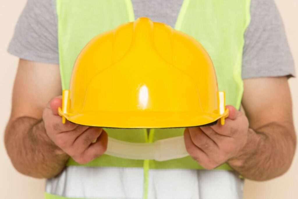 construction site safety equipment: worker holding a yellow helmet 